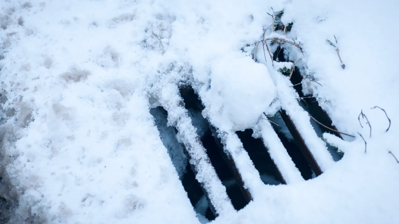 Snow covered storm drain blocked by ice and debris