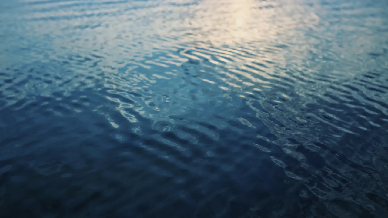 Rippling water with soft waves reflecting the light from the sky.
