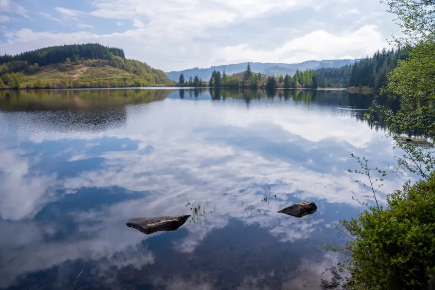 Loch Drunkie shot from low down with hills in the background and clouds reflected on the still water