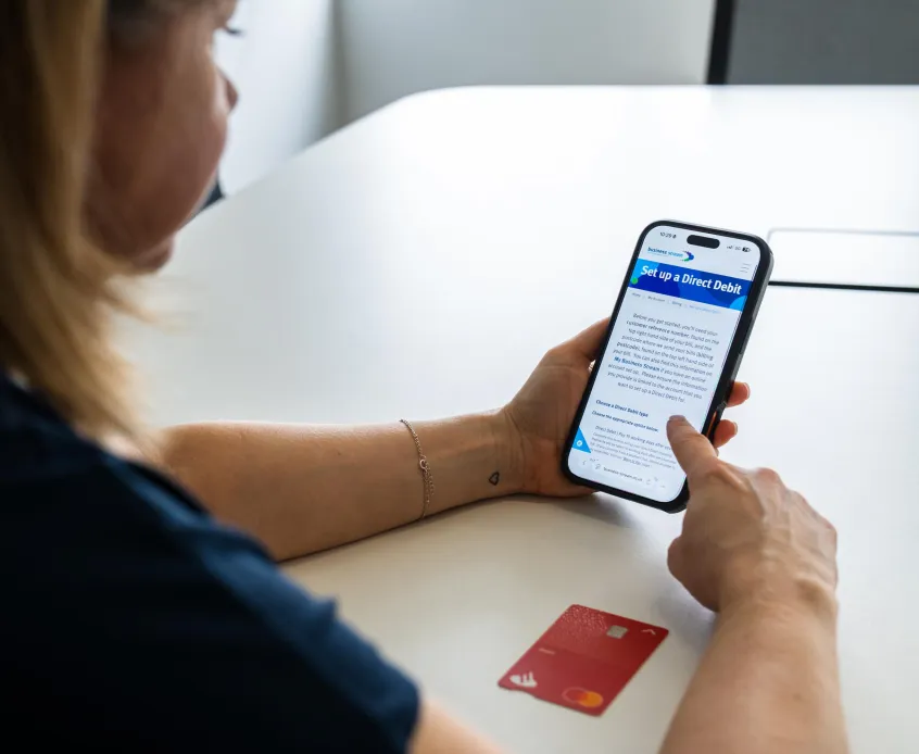 Over shoulder of a woman as she sets up a direct debit on her phone
