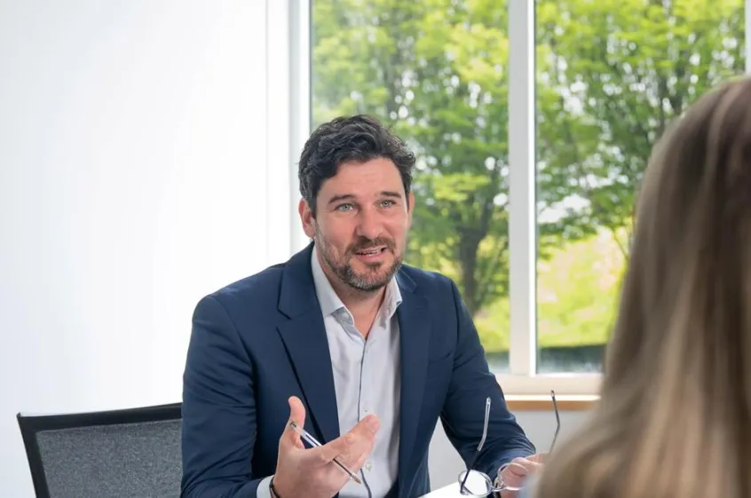 A man explaining something to a customer, from behind a desk