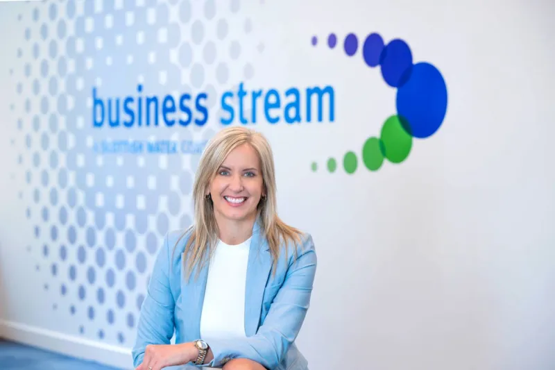 Jo Dow, CEO of Business Stream, sitting beneath the company logo
