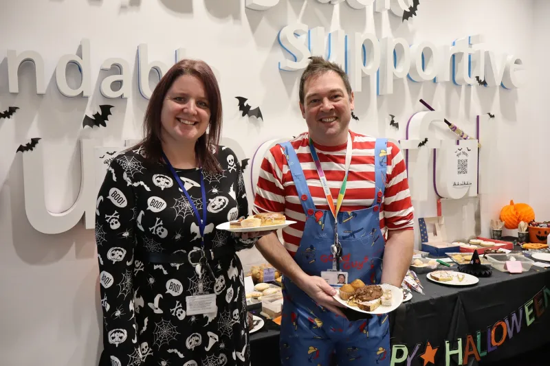 A woman and a man in halloween costumes at a bake sale 