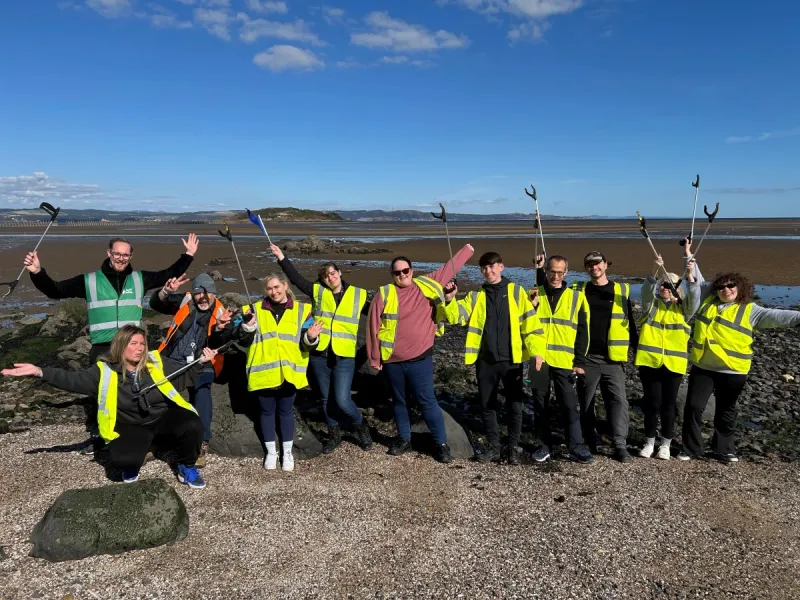 Large group of Business Stream colleagues celebrating litter pick on beach