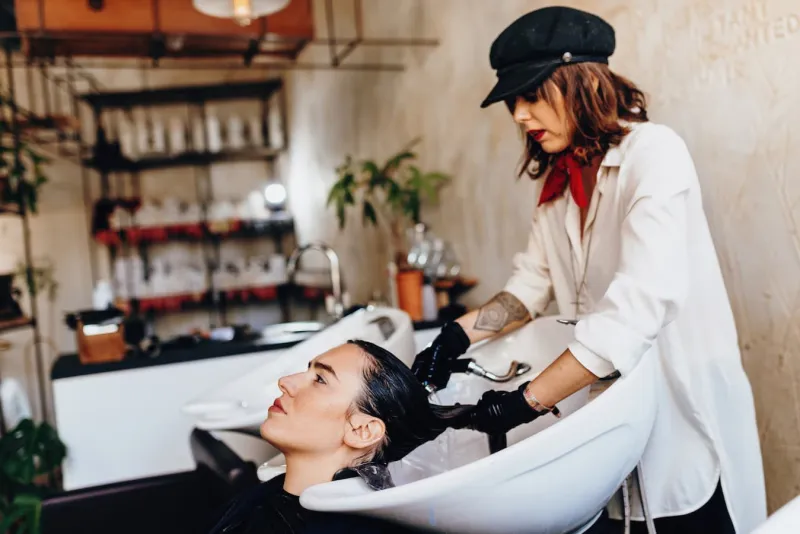 Female hairdresser washing woman's hair in salon