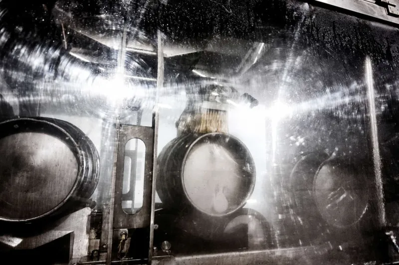 Barrels being machine cleaned in an industrial setting