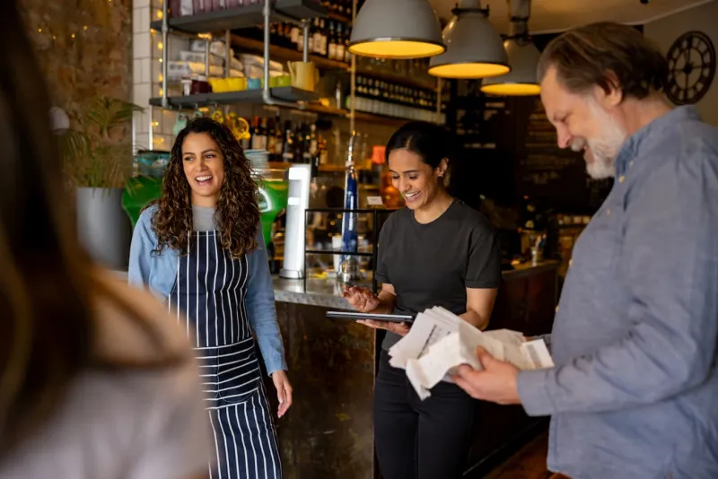 Bar owners and staff smiling, talking and looking at bills