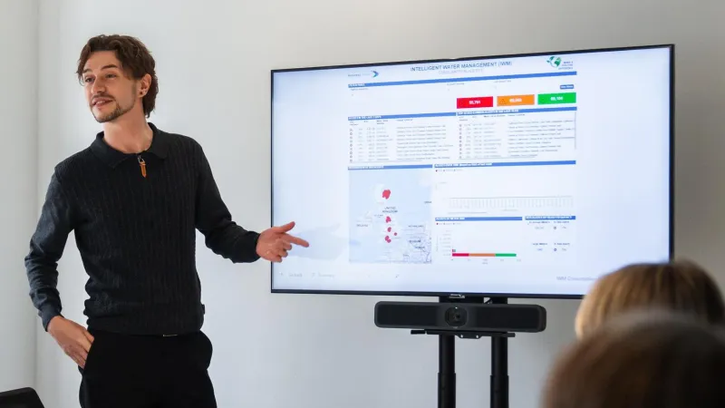 Man at large screen presenting data in a meeting room
