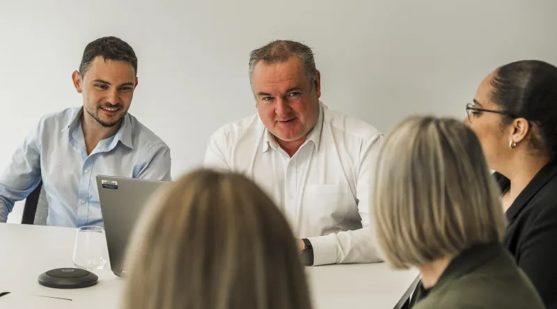 Close-up of two men and three women in a meeting scenario