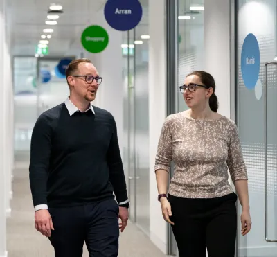 Man and woman chatting as they walk along a corridor