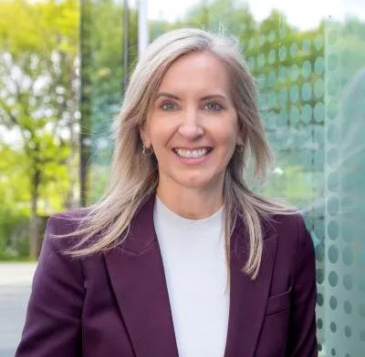 CEO Jo Dow with glass windows and trees in background